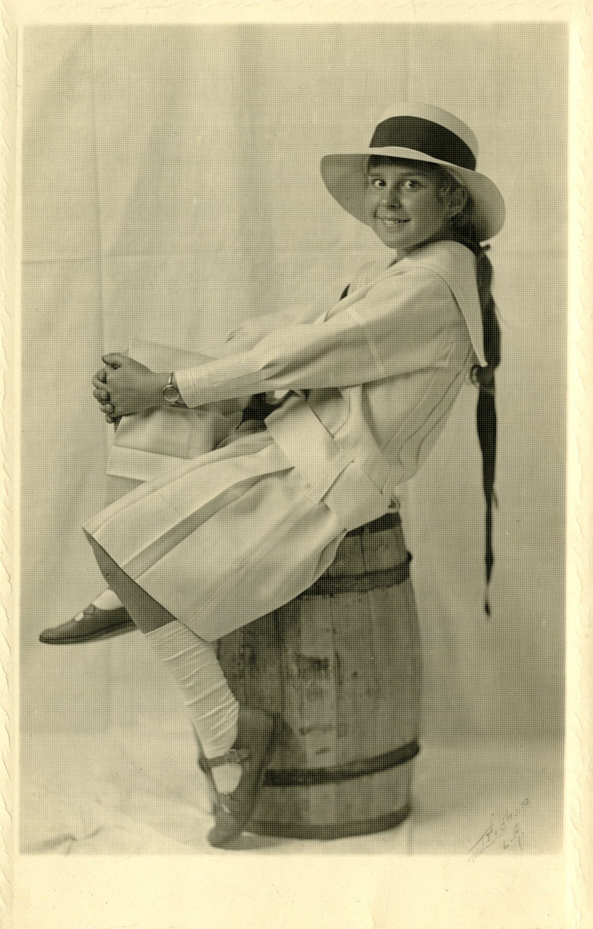 black and white photograph of a young girl in a white dress and straw hat with a black ribbon